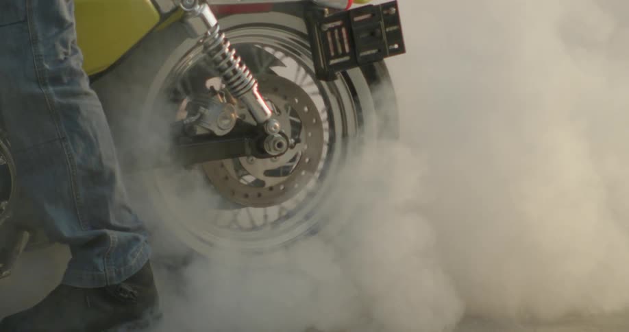 Motorcycle wheel turning with smoke rising from ground