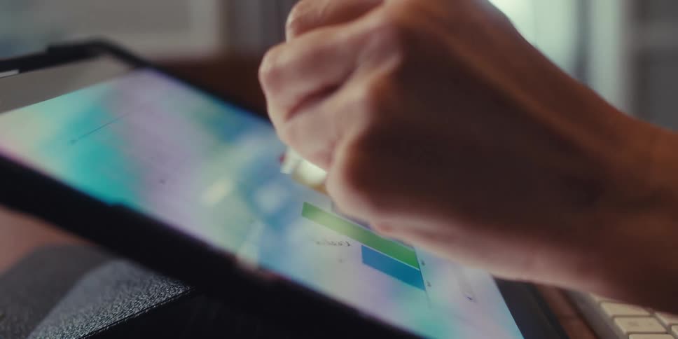 A woman is intently focused as she uses a digital stylus to create or design something on a tablet showcasing a moment of creativity and concentration