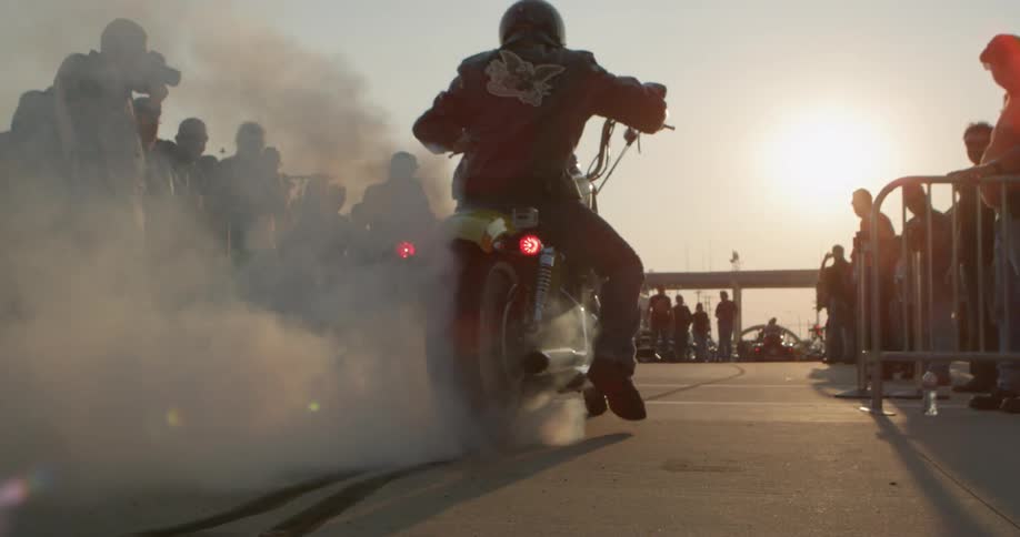 A man rides a motorcycle near a crowd