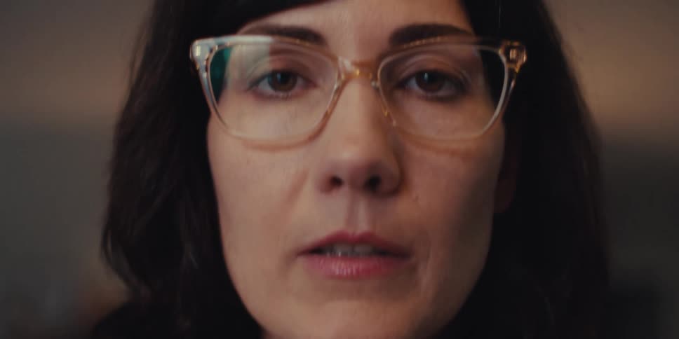 Woman in glasses and blazer typing on a keyboard