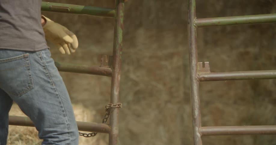 A person unwraps a chain and opens a gate