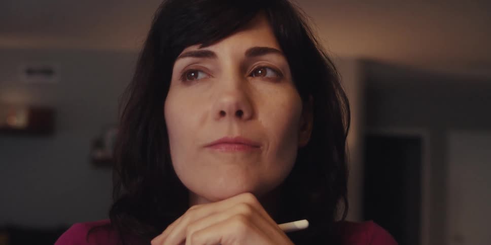 A woman in a room with a slight smile lost in thought
