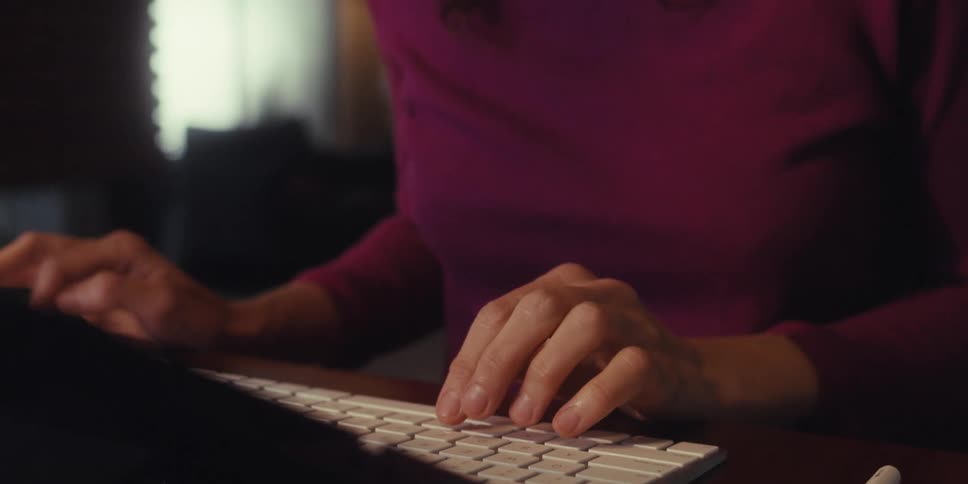 A woman sitting at a desk typing on the computer keyboard