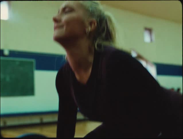 A determined woman lifts a heavy barbell in a gym straining with focus during a weightlifting exercise