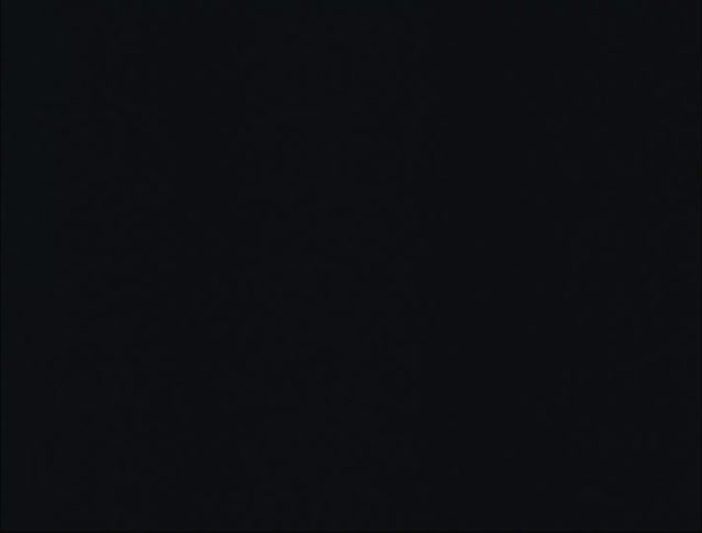 A young woman is in the gym lifting weights in a dark room with flickering lights