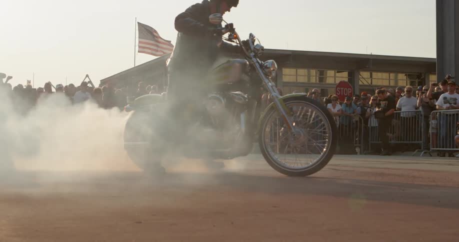 A man spinning tires on a motorcycle in a roadway