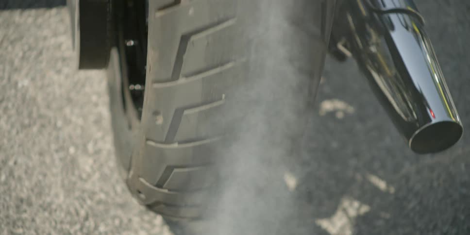 A motorcycle wheel is peeling out on the street