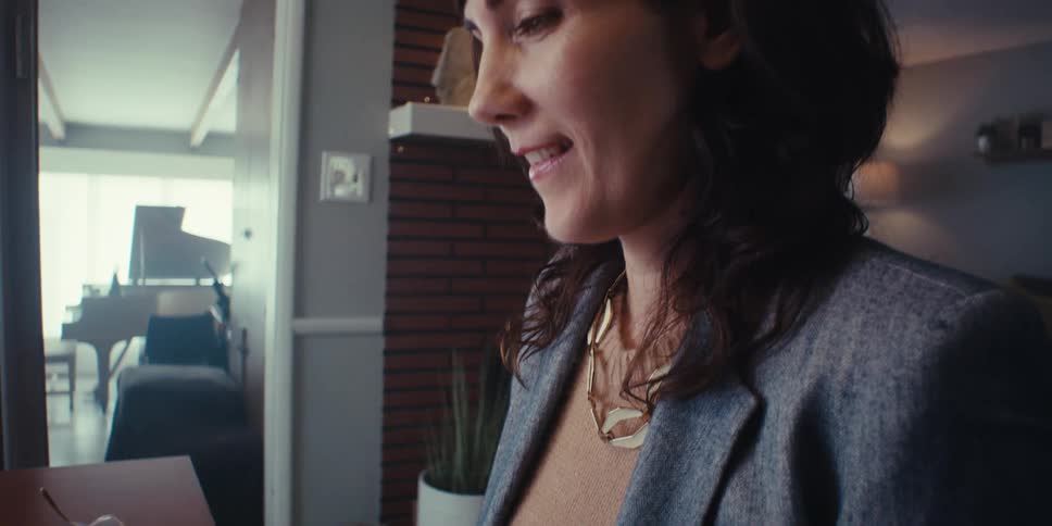 A woman works at a desk typing on a wireless keyboard in a home office environment lit by daylight