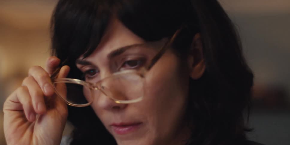 A woman puts on reading glasses and starts reading something in front of her
