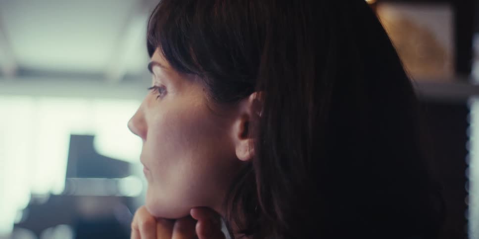 Woman stares into space briefly while sitting in front of a tablet displaying a graph