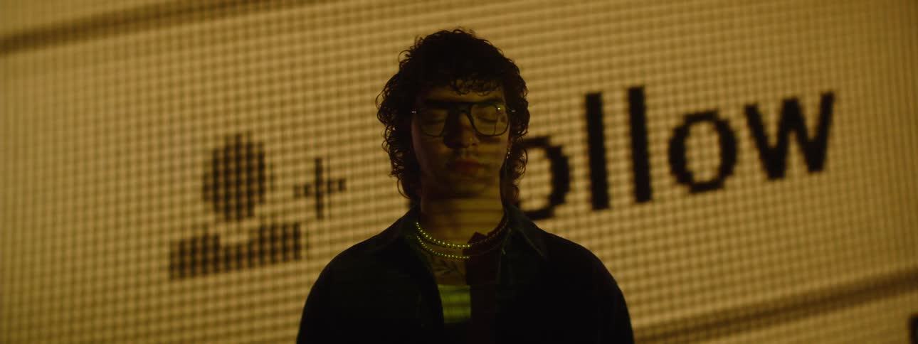 Man with glasses facing a large screen