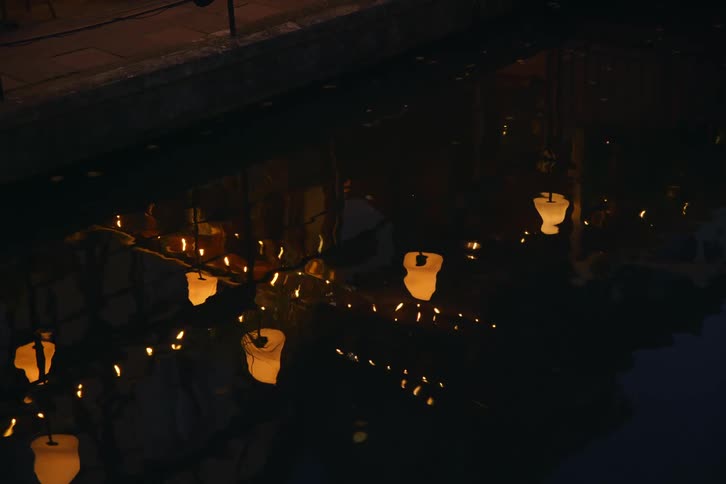 The lamp posts reflect on the water