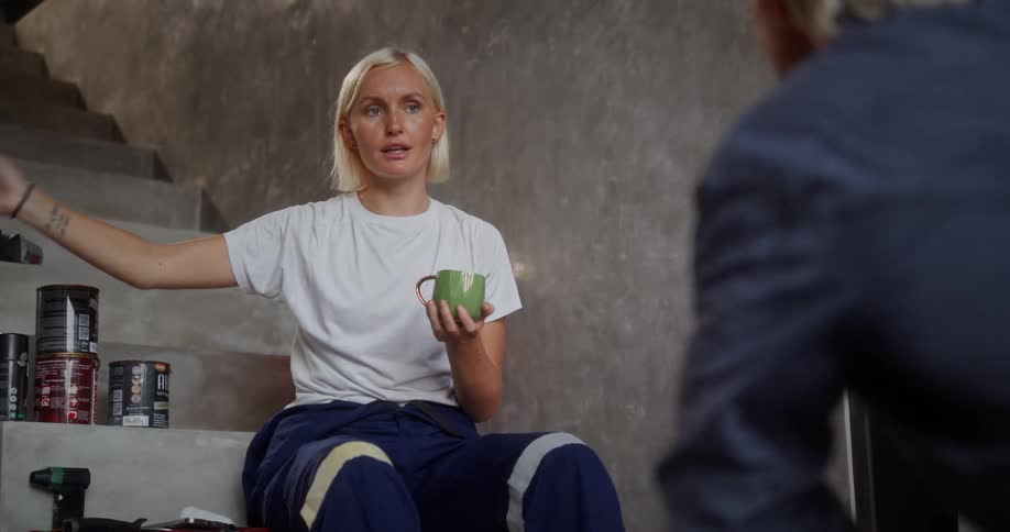 Woman sitting holding a green mug and talking to a man