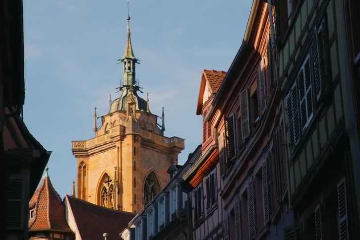A church with a tower stands at the end of the street surrounded by a series of residential buildings at midday