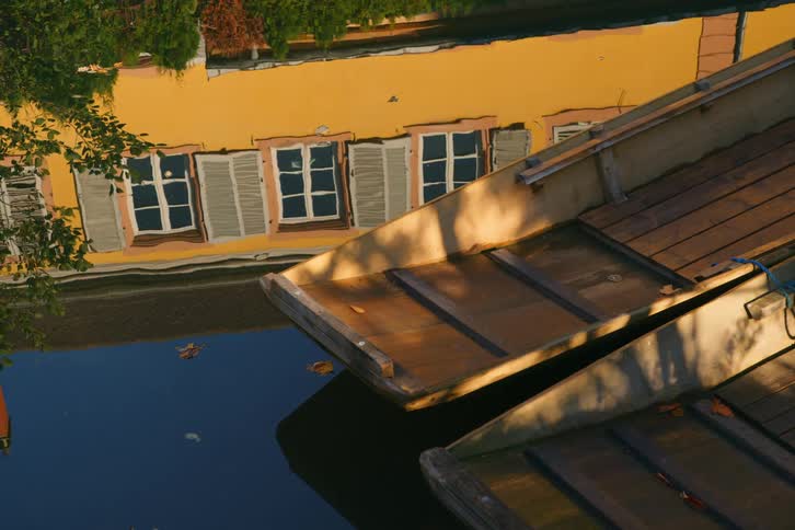 Wooden canoe on a lake reflecting the architecture of a yellow house in the background