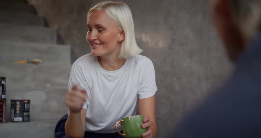 Woman sitting on stairs talking to another person and laughing out loud