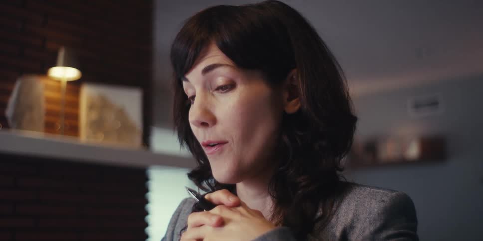 A woman smiles and gestures enthusiastically during a video call in an indoor setting