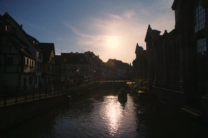 A picturesque canal scene at sunset in colmar france with a boat on the water and historic buildings lining the shore