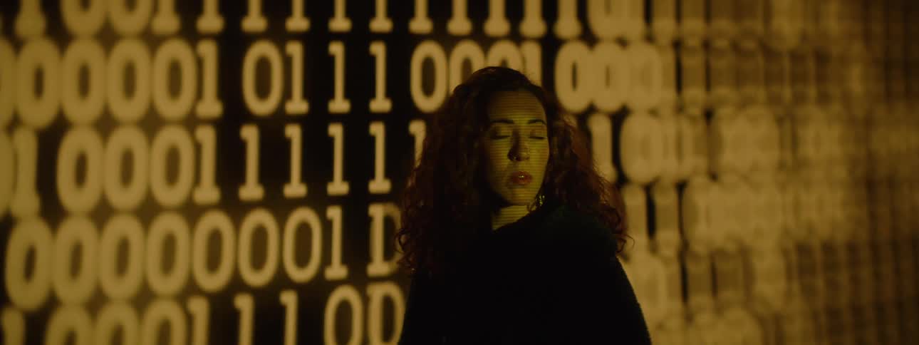 Numbers flash on the wall behind the woman