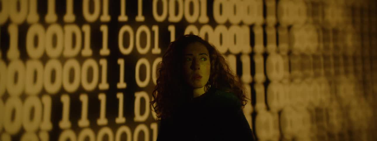Woman next to a large screen displaying numbers