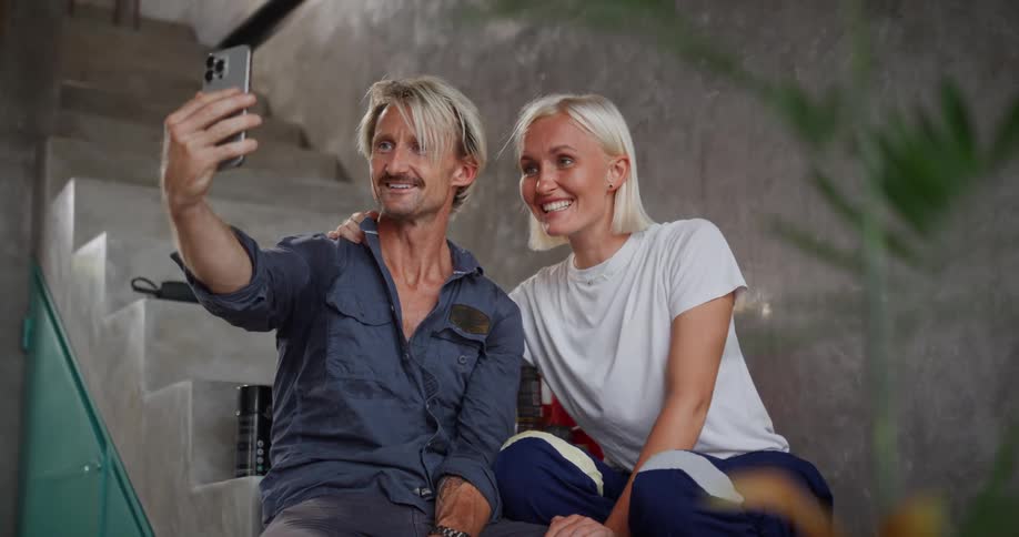 Smiling couple sitting on stairs taking photo