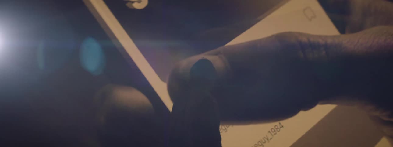 A person walking up to a huge screen showing a persons finger sliding across a cell phone screen