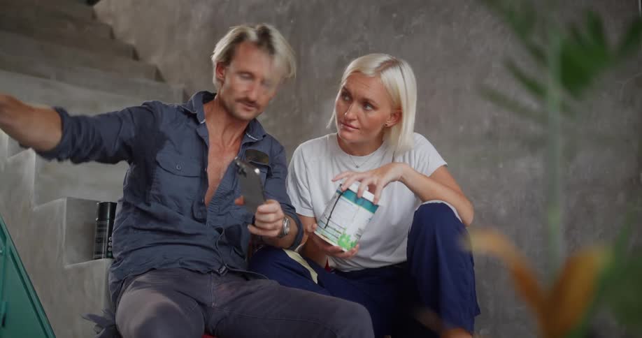 A man and a woman are sitting and discussing something while looking at a phone and a container