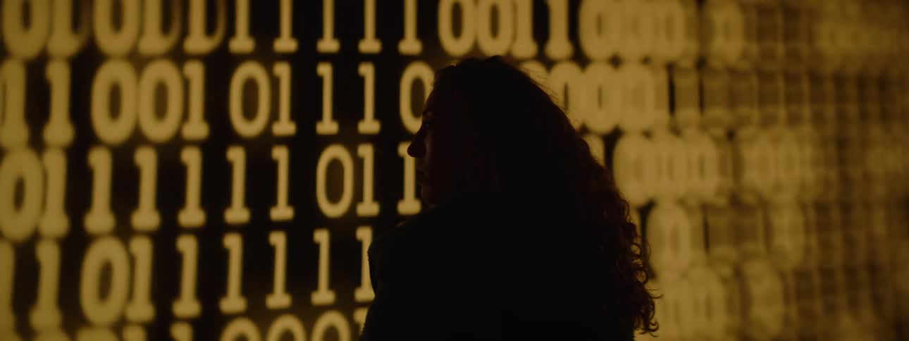 A woman is looking at a projection of moving numbers