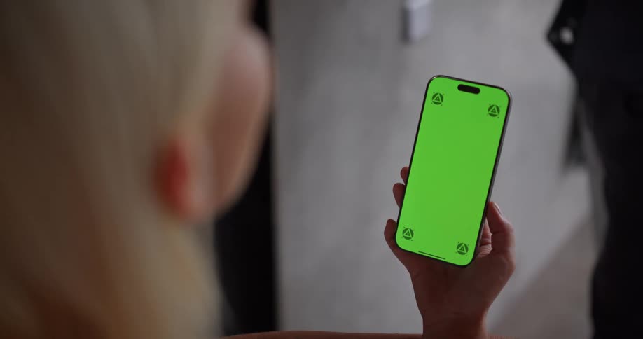 Woman holding a cell phone with a green screen