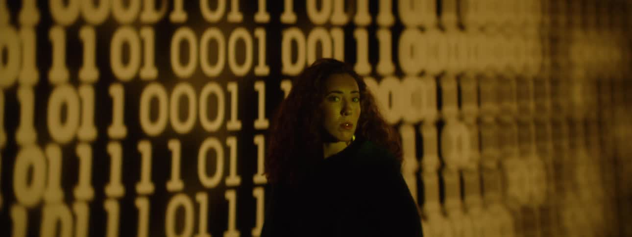 Curlyhaired woman next to a screen displaying a code of numbers