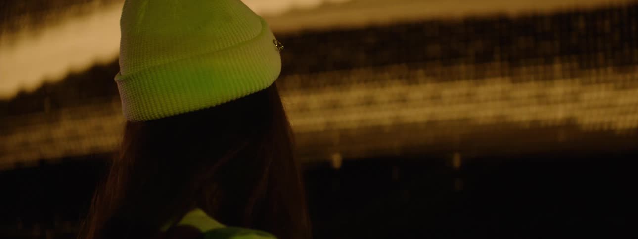 A woman wearing a yellow beanie is standing in front of a large projector screen