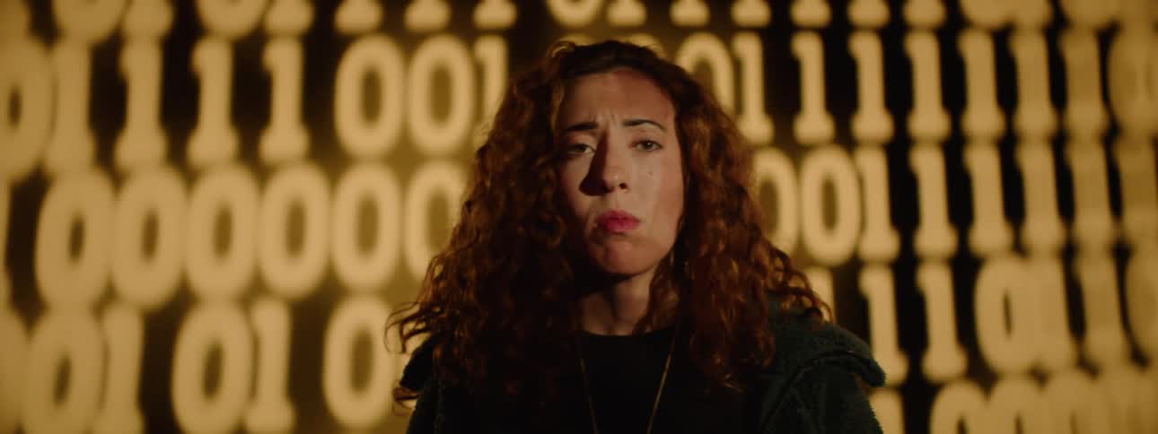 A woman looks worried as the numbers flash on the wall behind her