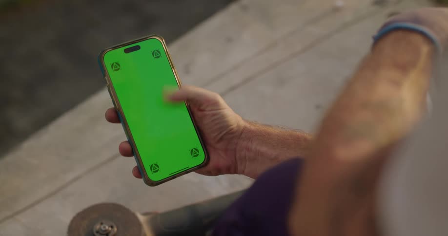 Man holding a cell phone and moves his thumb across the green screen