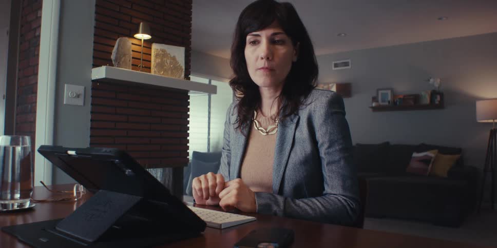 Woman in blazer sitting typing on a keyboard connected to a tablet