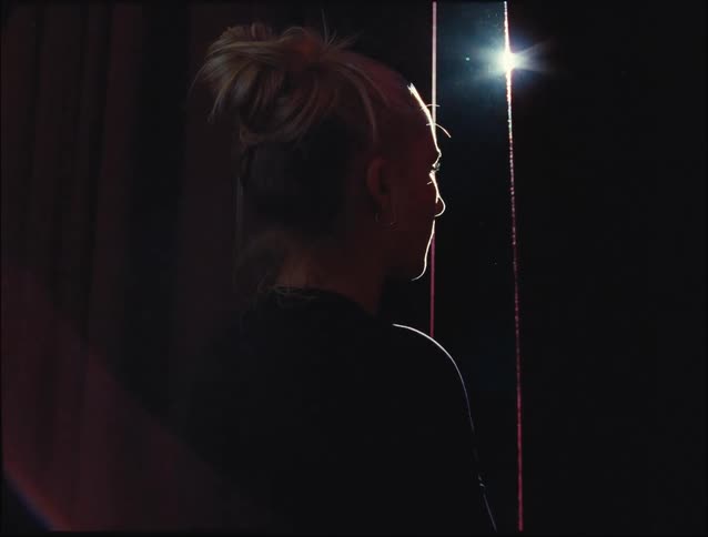 Woman looking through the curtains of a window at night