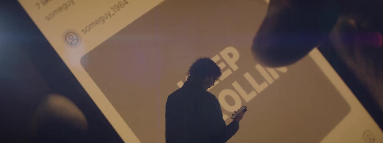 A person on their phone is silhouetted against a scrolling screen that reads keep scrolling symbolizing digital addiction