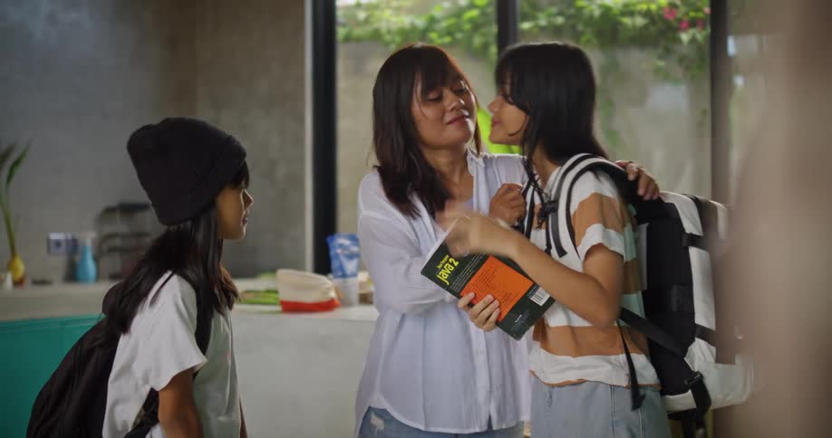 A mother kisses her children goodbye as they head to school