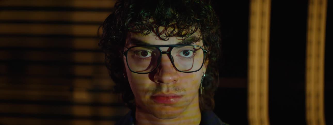 A man wearing glasses is illuminated with multiple light projections