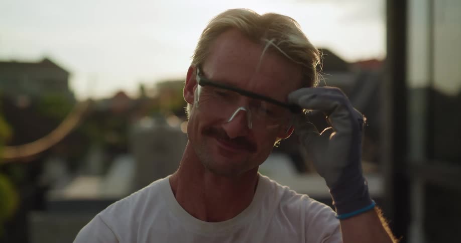A man smiles and removes his glasses