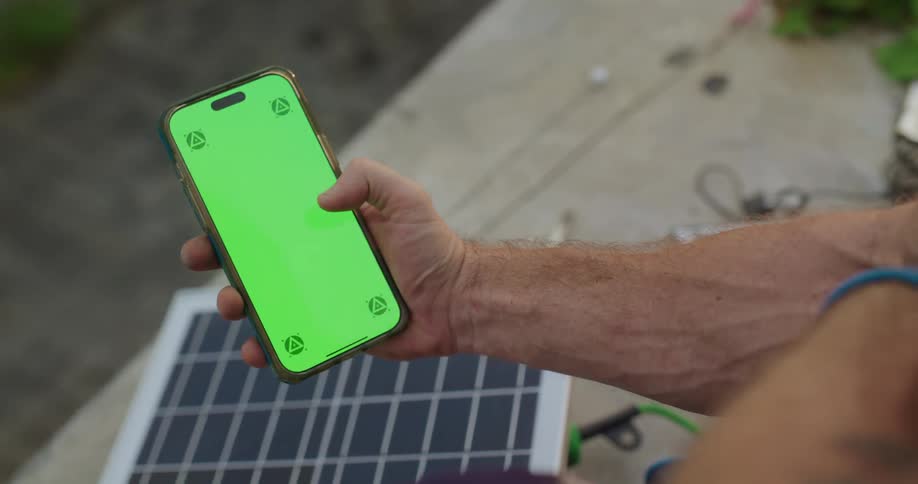 Man holding a cell phone and moves his thumb across the green screen