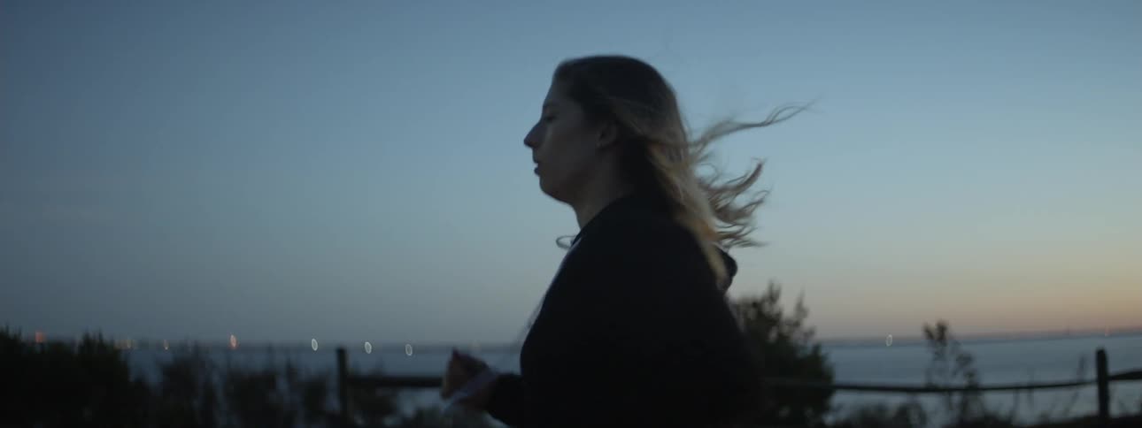 Woman jogs outside at sunset next to water