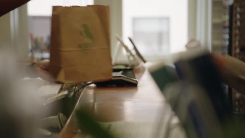 A worker hands a customer her bag in a store