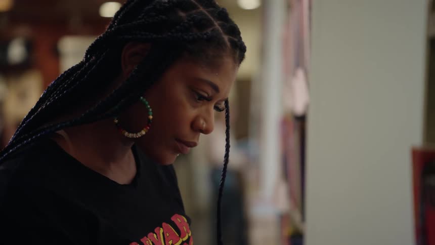 Woman observes something with a slight smile as she walks between shelves