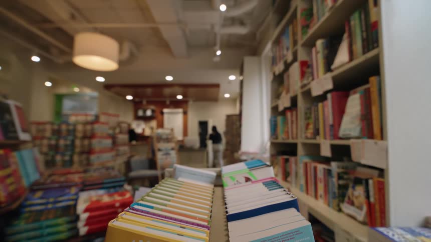 Point of view pushing a cart of hardcover books across a book store