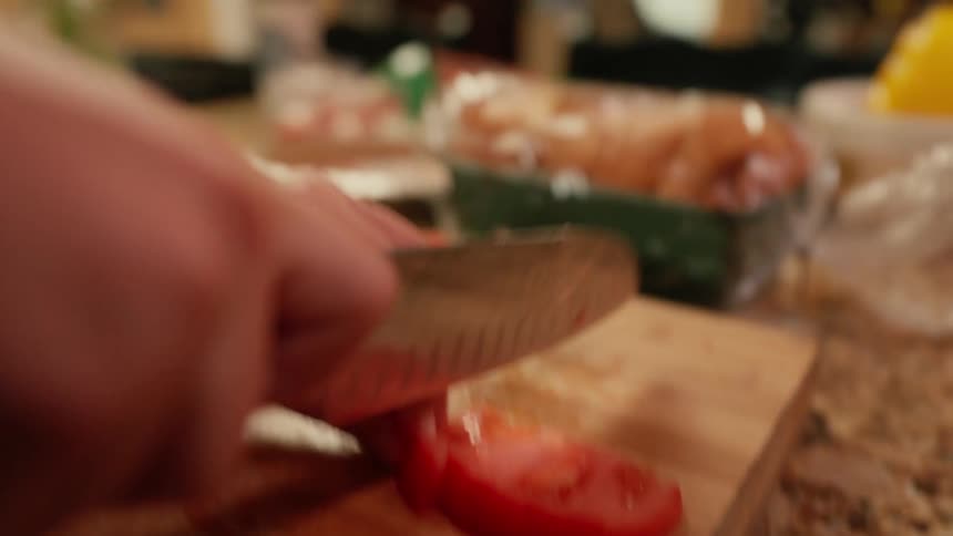 Person uses a knife to slice tomatoes on a chopping board