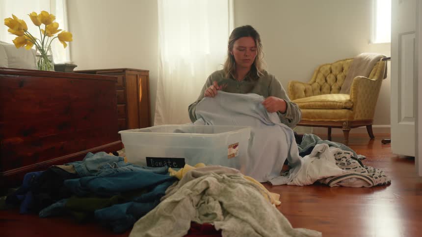 The woman folds the cloth then places it in a plastic container