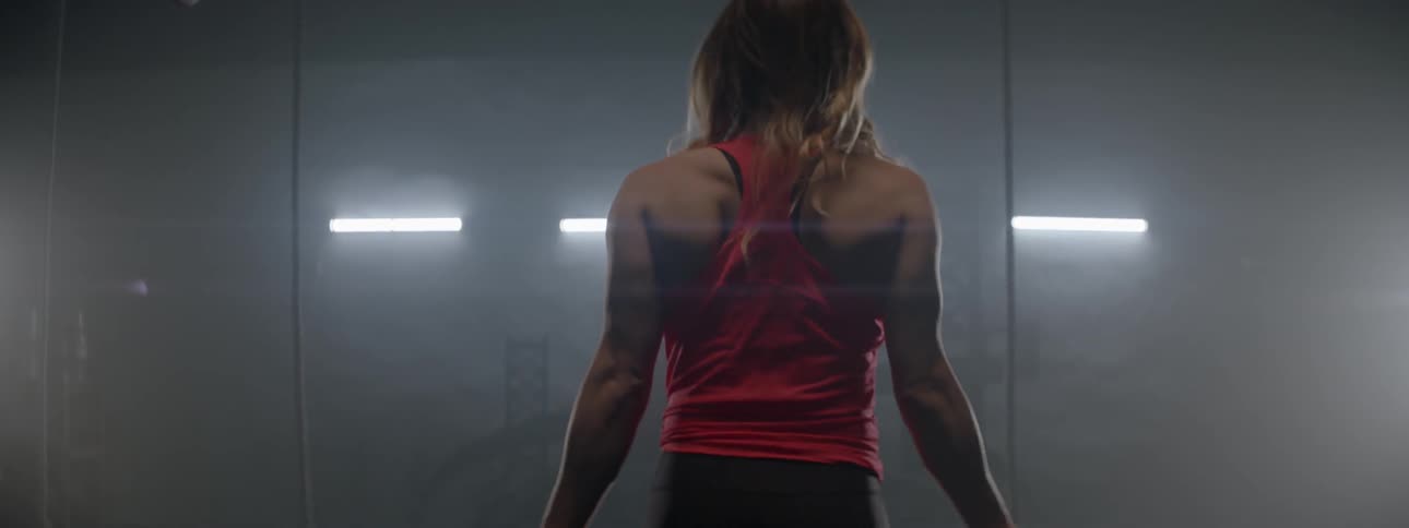 A woman uses a jumping rope in a gym with bright fluorescent lights