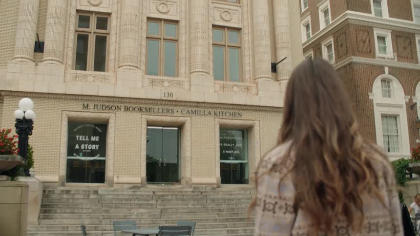 Woman walking outdoors towards commercial establishment