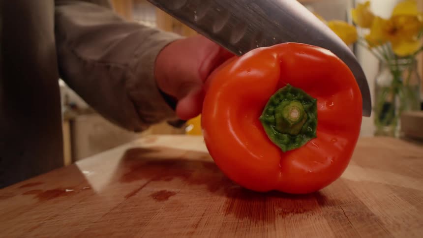A person cuts colorful bell peppers in a bright kitchen