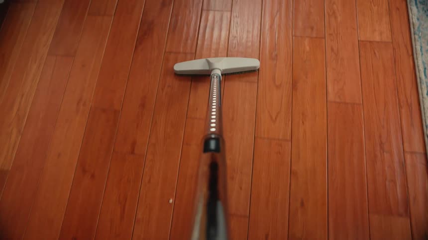 A person is vacuuming the wood flooring